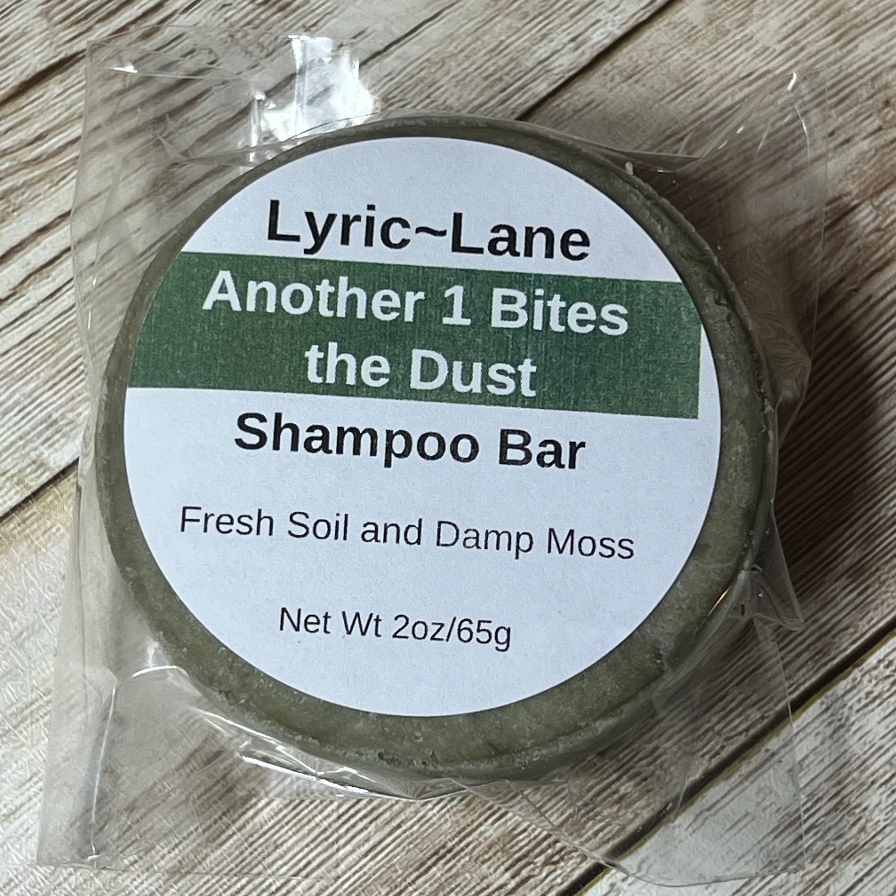 Lyric-Lane shampoo bar with fresh soil and damp moss scent, labeled Another 1 Bites the Dust - Smells Like Dirt. On Purpose.