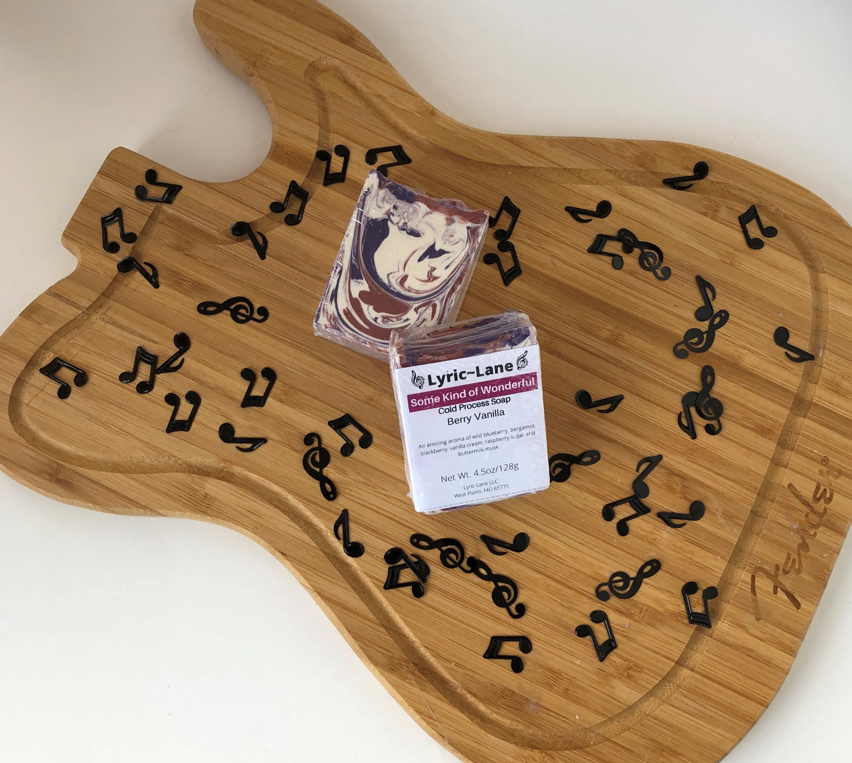 Two 4oz bars of Some Kind of Wonderful cold processed soap on a wood guitar shape with scattered music notes. Scented with berry vanilla. Designed with a maroon, purple and white swirl pattern. Made by Lyric-Lane