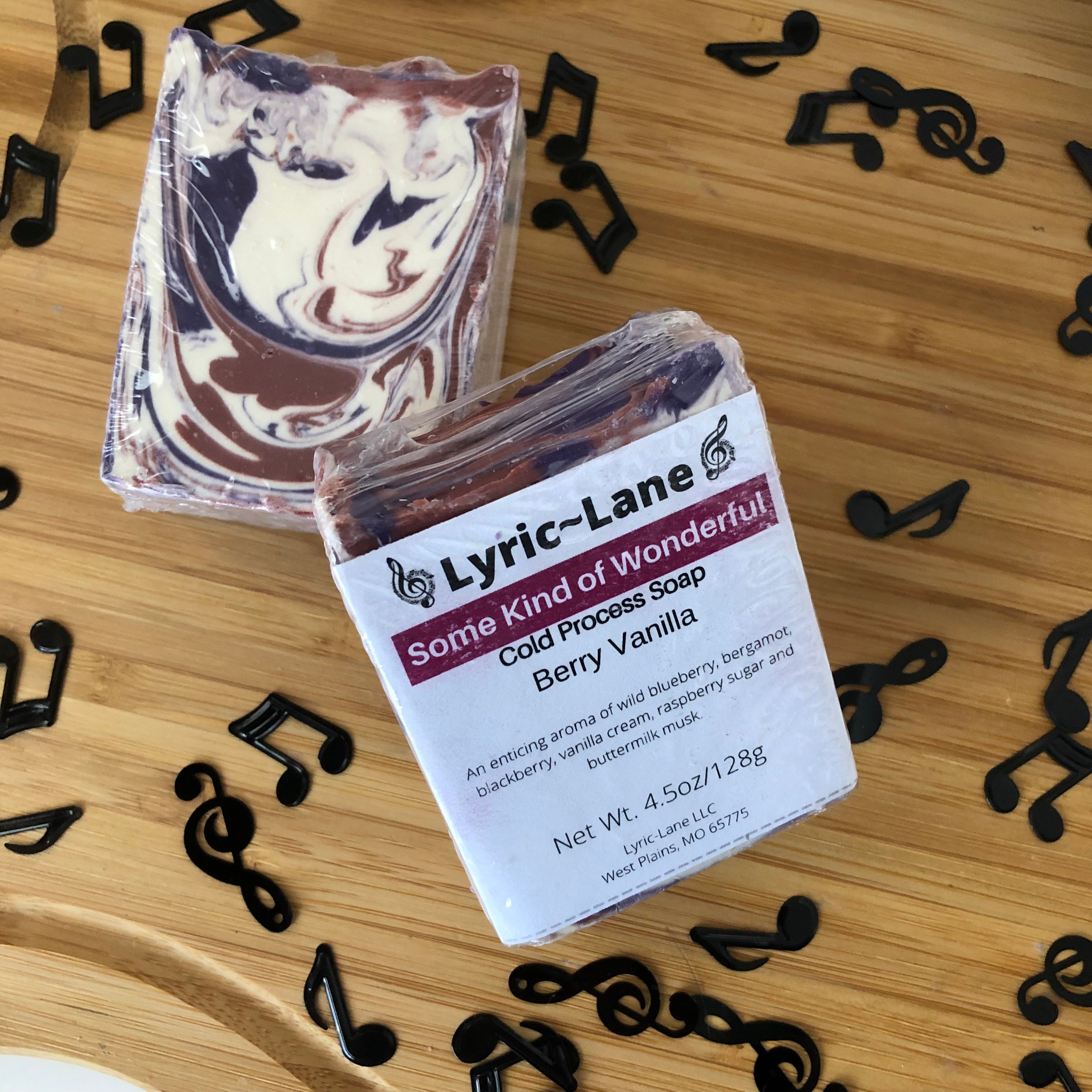 Two 4oz bars of Some Kind of Wonderful cold processed soap on a wood guitar shape with scattered music notes. Scented with berry vanilla. Designed with a maroon, purple and white swirl pattern. Made by Lyric-Lane