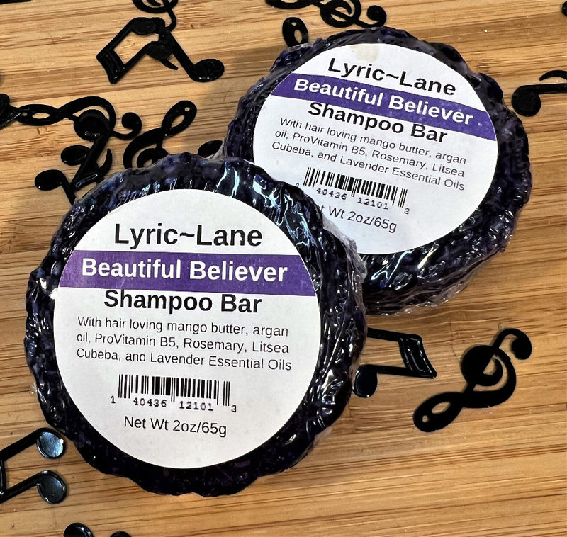Two 2oz round bars of Beautiful Believer Shampoo Bars. Purple bars scented with rosemary, litsea cubeba, and lavender essential oils on a wood guitar shape with scattered music notes. Made by Lyric-Lane
