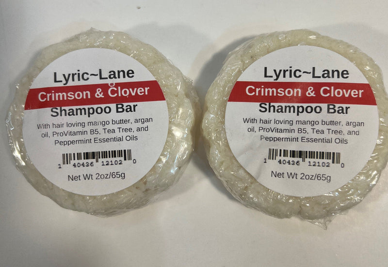 Two 2oz round bars of Crimson and Clover Shampoo Bars. White bars laying side by side scented with tea tree and peppermint essential oils on a white background. Made by Lyric-Lane