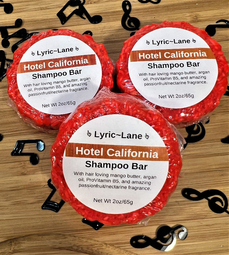Three 2oz round bars of Hotel California Shampoo Bars. Crimson bars scented with passionfruit and nectarine on a wood guitar shape with scattered music notes. Made by Lyric-Lane