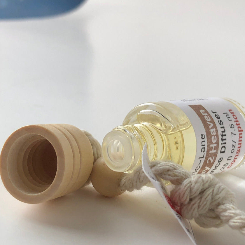 A close up shot of an aromatherapy diffuser bottle laying on its side with the wooden lid off and showing the rubber plug protecting the fragrance in the bottle from spilling. Made by Lyric Lane Soap.