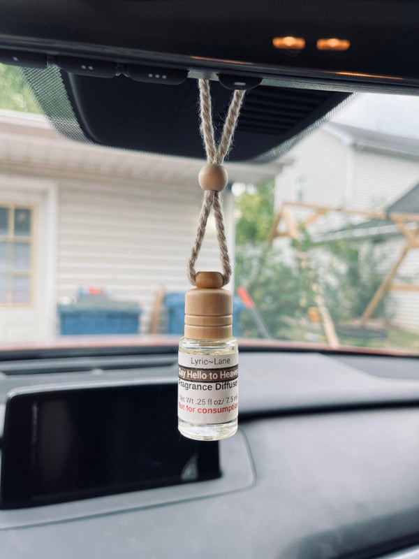 Say Hello to Heaven glass diffuser bottle hanging from rearview mirror in a car by beaded rope
